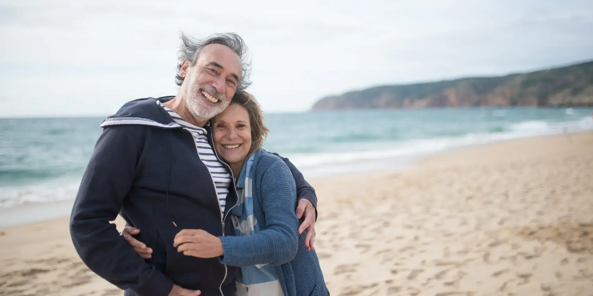man and woman hugging on the beach 